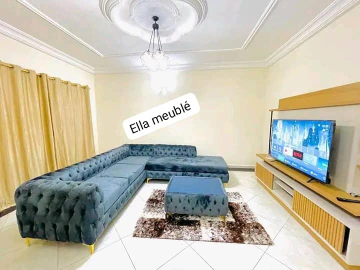 a living room with a large couch and a television at Appartement Ella Meublé in Yaoundé