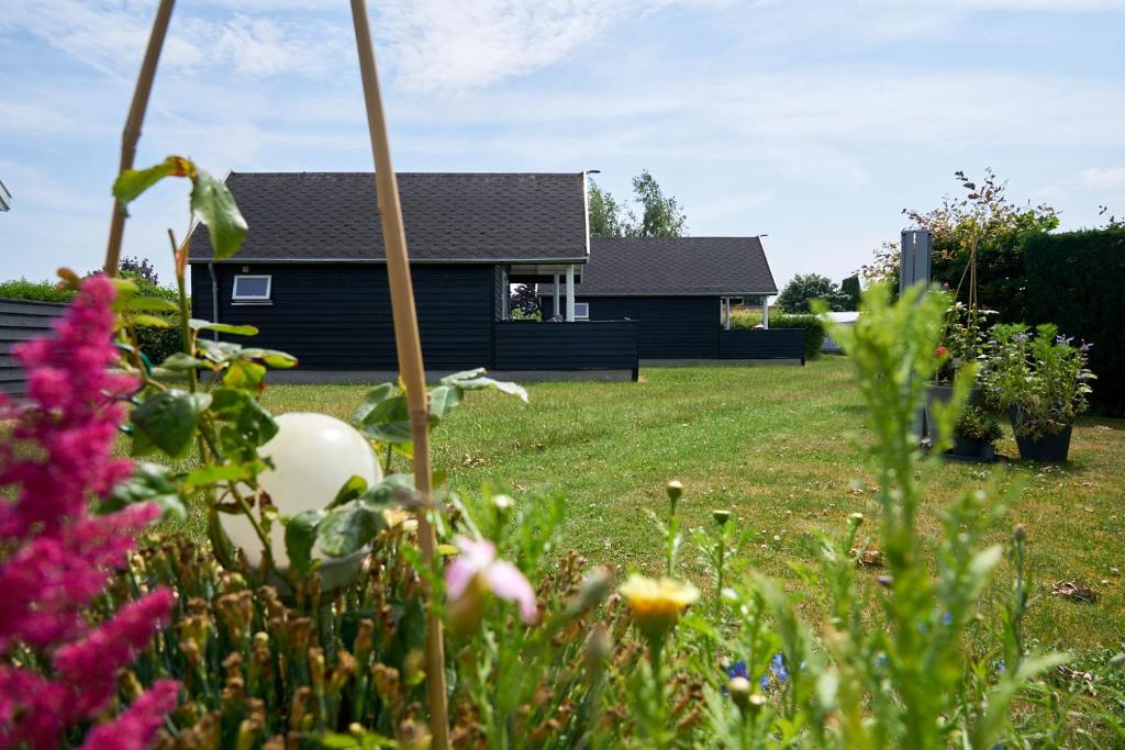 a house in a yard with flowers in the foreground at Stevns Camp in Strøby