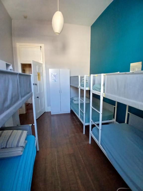 a room with three bunk beds and a hallway at 1849 Backpackers Albany in Albany