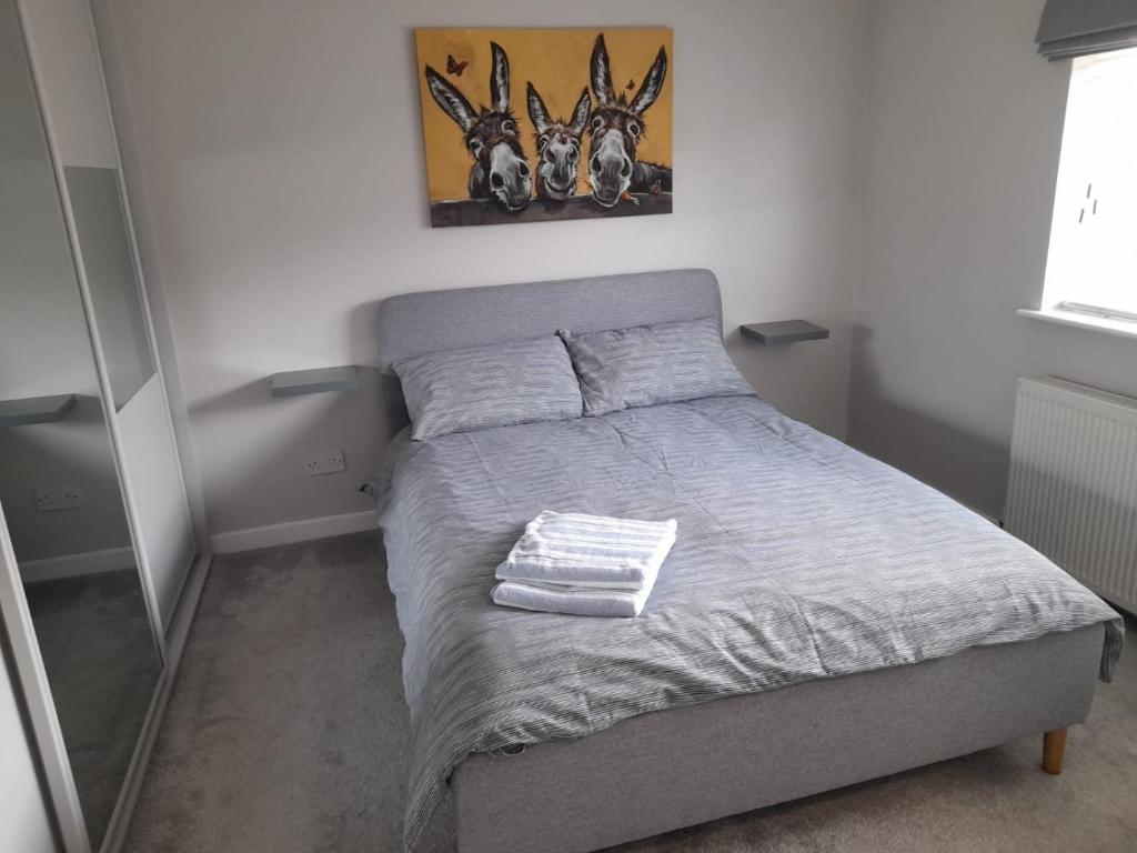 a small bedroom with a bed with a gray bedspread at Stylish house in Roydon in Roydon