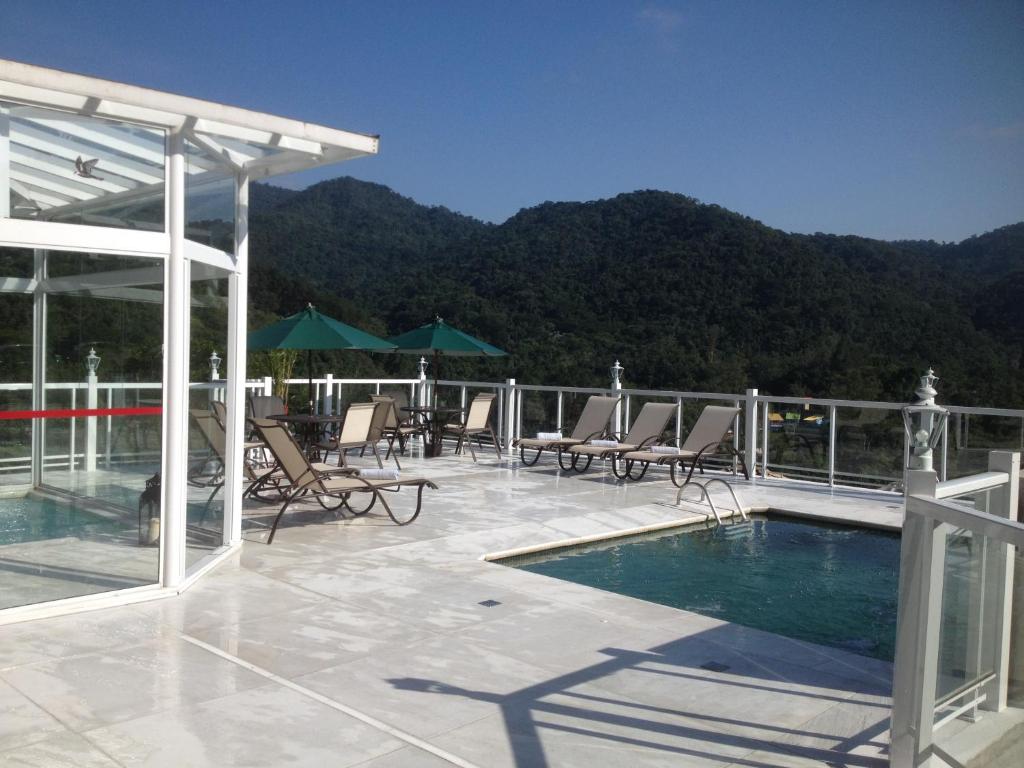 a patio with chairs and a swimming pool on a roof at Pousada Terraço Penedo in Penedo