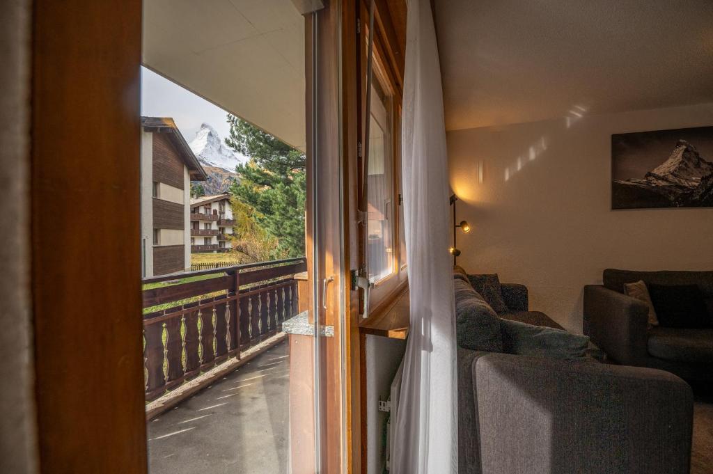 a room with a balcony with a couch and a window at Fabi`s Horu Lodge in Zermatt