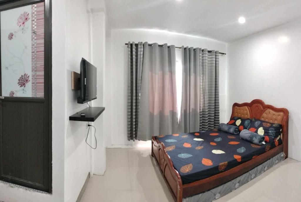 una camera da letto con un letto e una TV a schermo piatto di Baguio transient house kalachuchi unit a Baguio