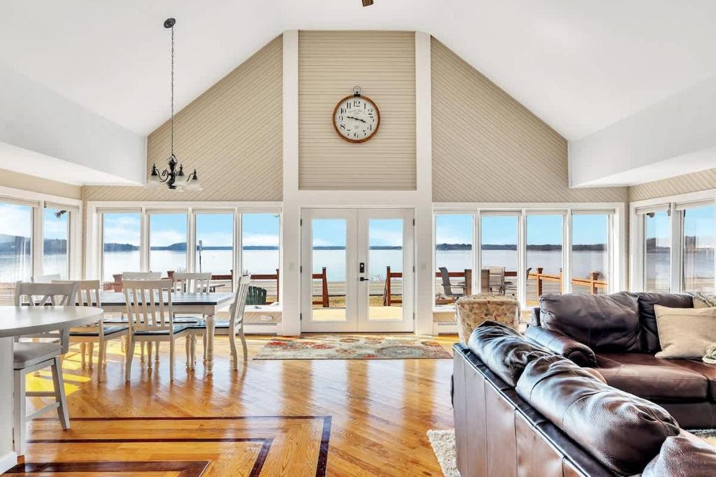 Una sala de estar con una mesa y un reloj en la pared. en Lake Access 5 Minutes from Track, en Saratoga Springs