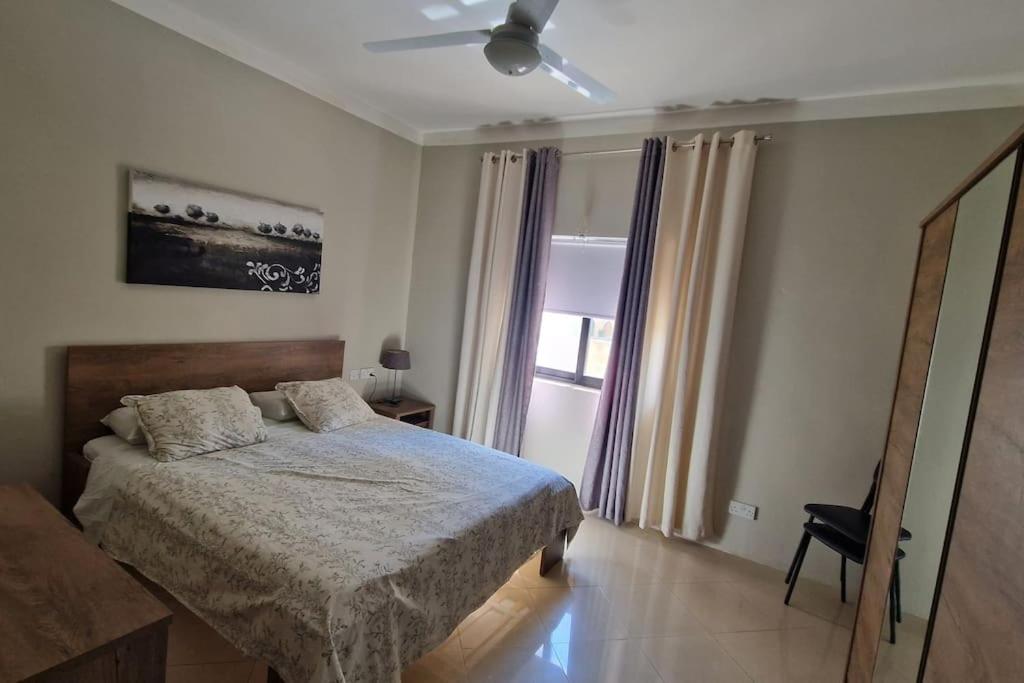 un dormitorio con una cama y una ventana en Peaceful & Modern Corner Apartment, en Qala