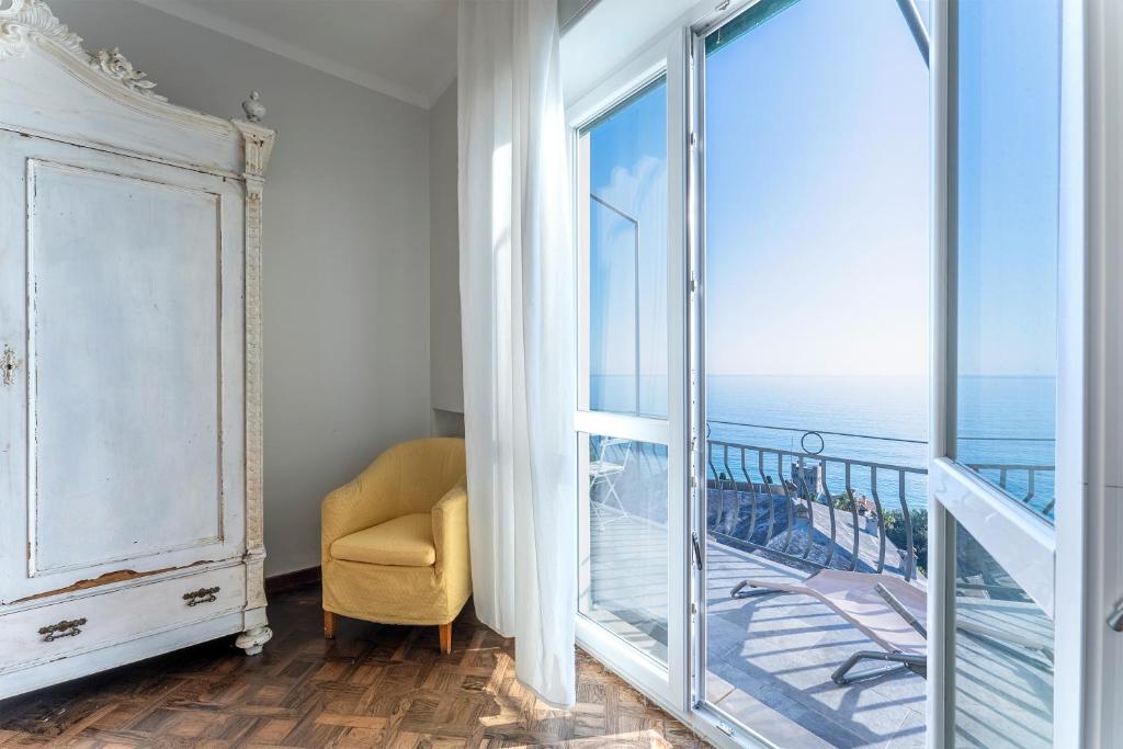 a room with a balcony with a chair and a window at Breath-taking Portofino Promontory Seaview in Pieve Ligure
