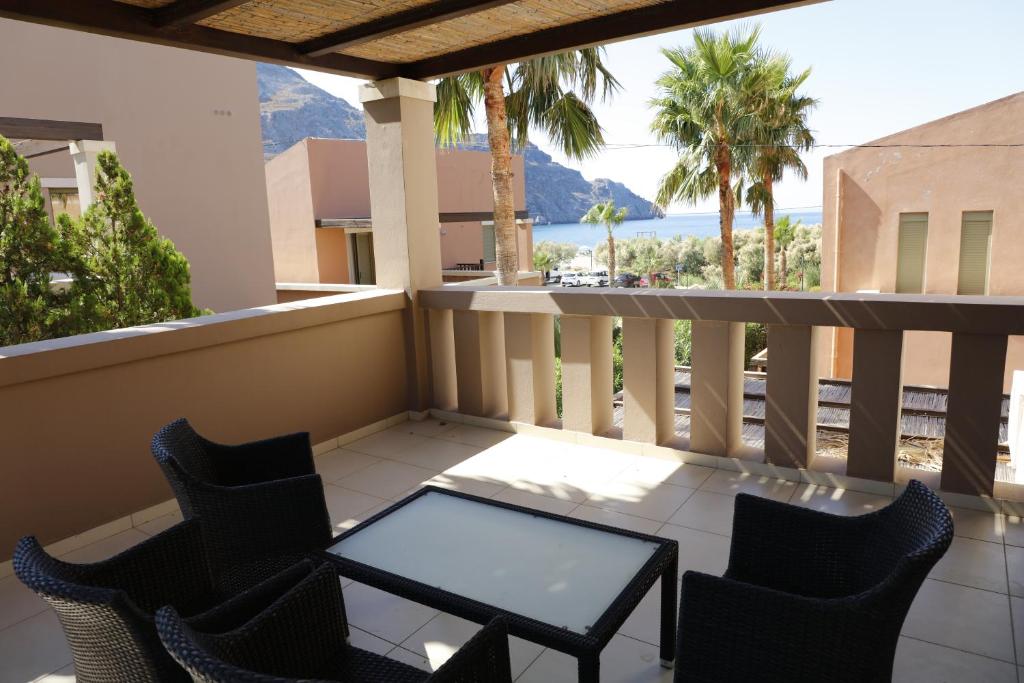 a balcony with chairs and a table and a view of the ocean at Plakias Seaside Maisonette in Plakias