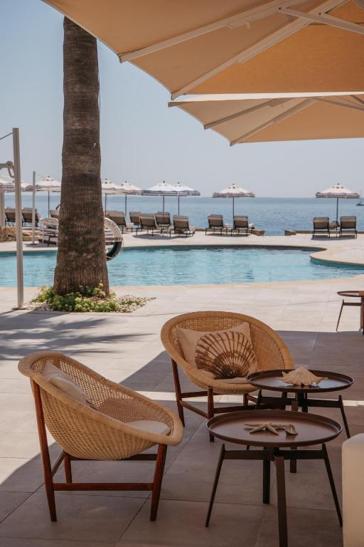 a patio with two chairs and a table and an umbrella at Hotel de Mar Gran Meliá - Adults Only - The Leading Hotels of the World in Illetas
