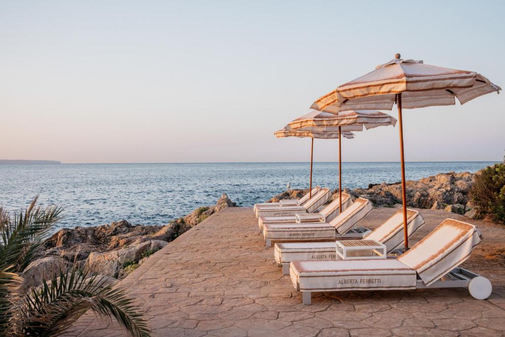 a row of lounge chairs and umbrellas on the beach at Hotel de Mar Gran Meliá - Adults Only - The Leading Hotels of the World in Illetas