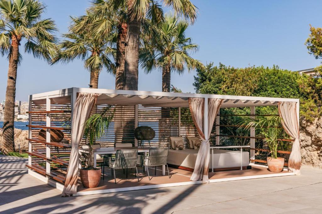 a patio with a gazebo with palm trees at Hotel de Mar Gran Meliá - Adults Only - The Leading Hotels of the World in Illetas