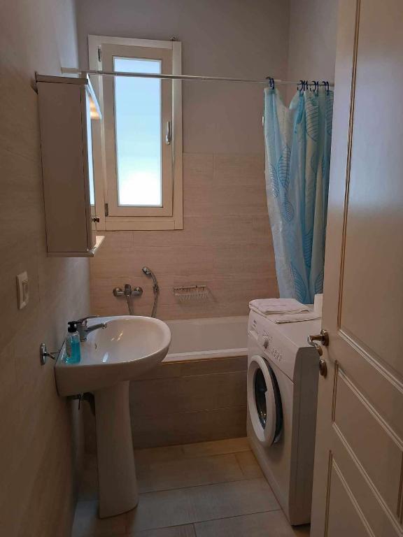 a bathroom with a sink and a bath tub at Andros Guesthouses in Andros