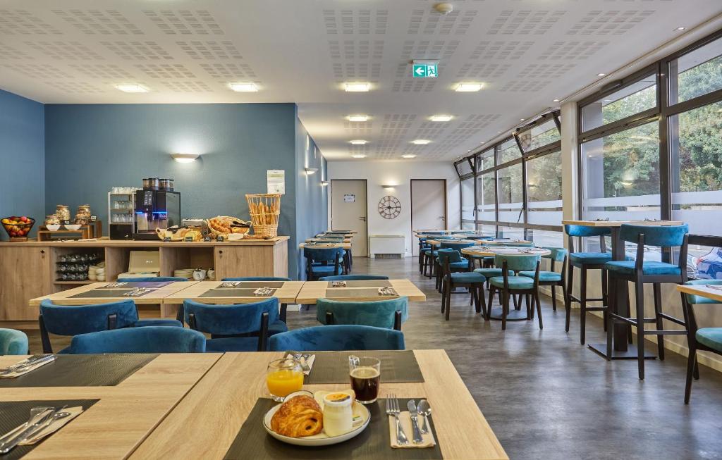 a restaurant with wooden tables and blue chairs at Résidence Odalys Archipel in La Rochelle