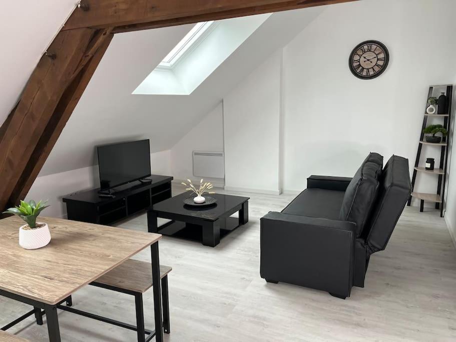 - un salon avec un canapé noir et des tables dans l'établissement Le Bois Lumineux - T2 proche de la Gare, à Cambrai