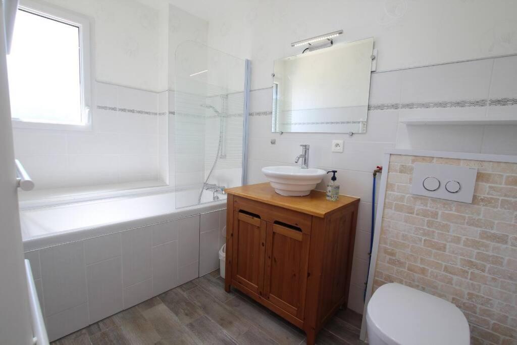 a bathroom with a sink and a tub and a toilet at MAISON DE VACANCES 4 Clés - BORD DE MER DENNEVILLE PLAGE in Denneville