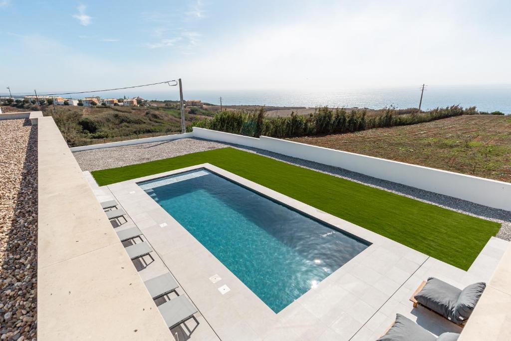 a swimming pool with a view of the ocean at Villa Locki in Lourinhã