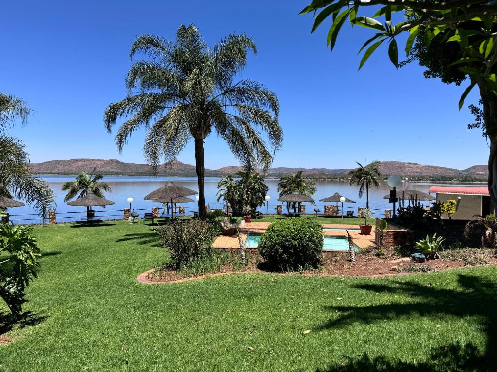 a resort with a palm tree and a body of water at Olives by Agnes in Hartbeespoort