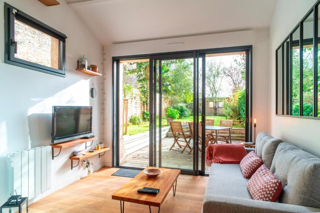un salon avec un canapé et une télévision dans l'établissement Escale jardin - Joli apt proche gare avec jardin, à Vannes
