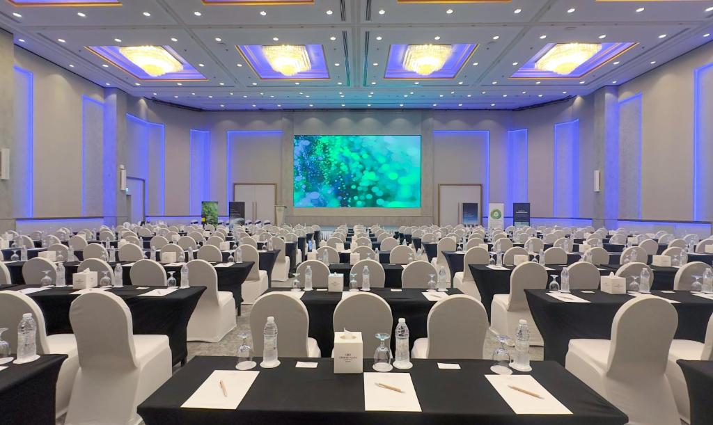 a conference room with tables and chairs and a screen at Crowne Plaza Bahrain by IHG in Manama