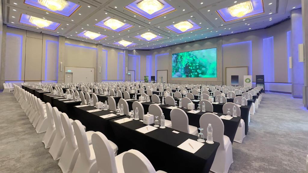 a large room with tables and chairs and a screen at Crowne Plaza Bahrain by IHG in Manama