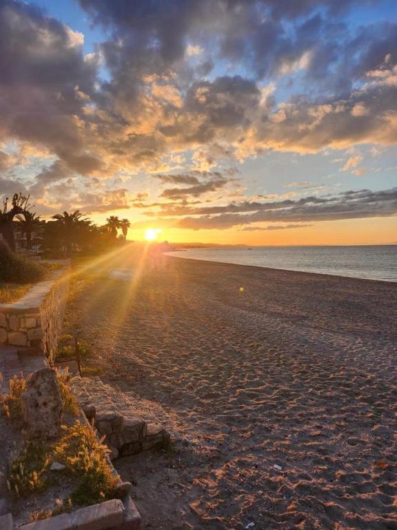 a sunset on a beach with the sun setting at Luxury on the beach apartment in Hanioti