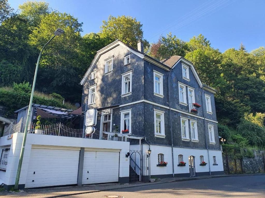 a large stone house with a white garage at Villa Burgau, C&H in Monschau