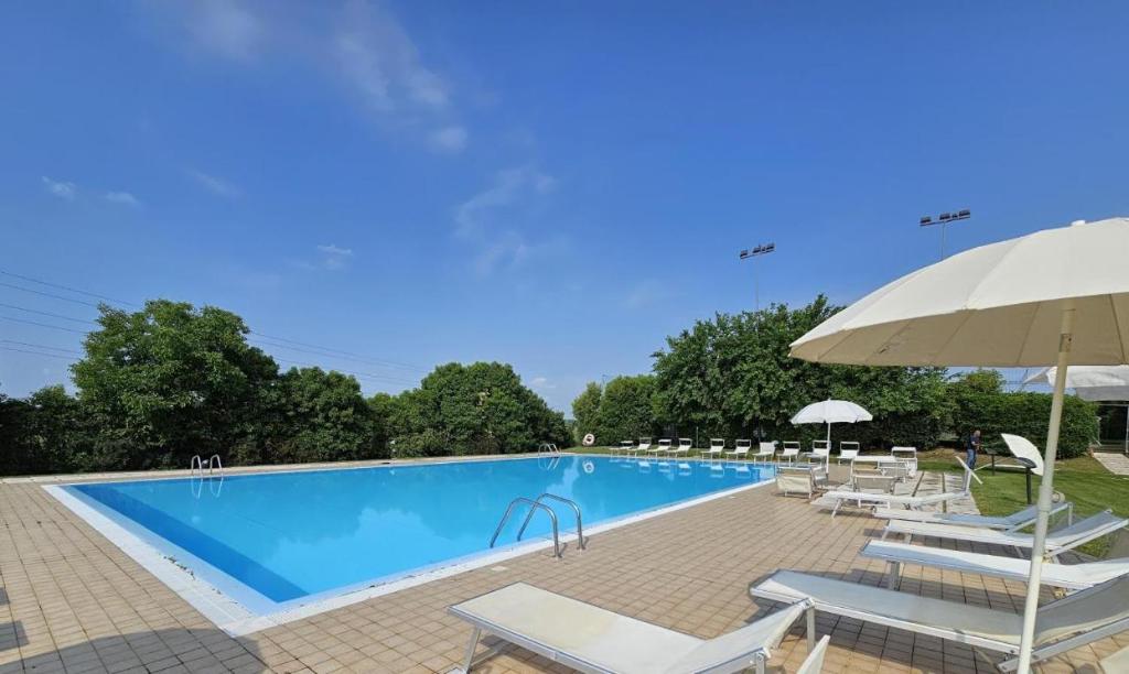 una gran piscina con sillas y sombrilla en Wendy Apartment- Twobedroom & Pool & ParkPrivateFree & Sports, en Desenzano del Garda