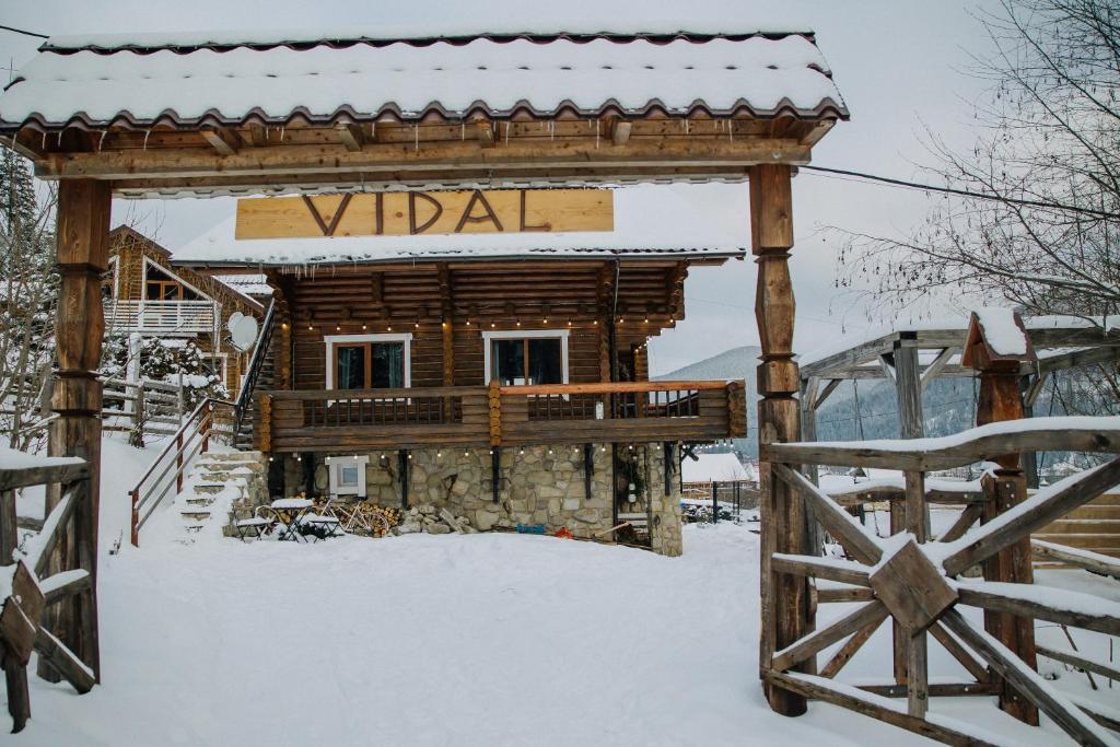 Una cabaña de troncos en la nieve con un letrero que dice Vada. en Vidal, en Tatariv