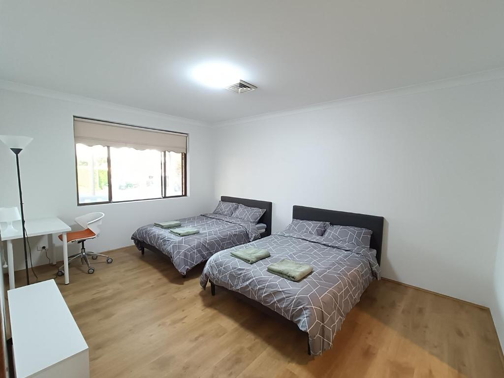 una camera da letto con due letti e una scrivania di Cozy Family Room with Private Bathroom in Spacious Home - M8 a Merrylands