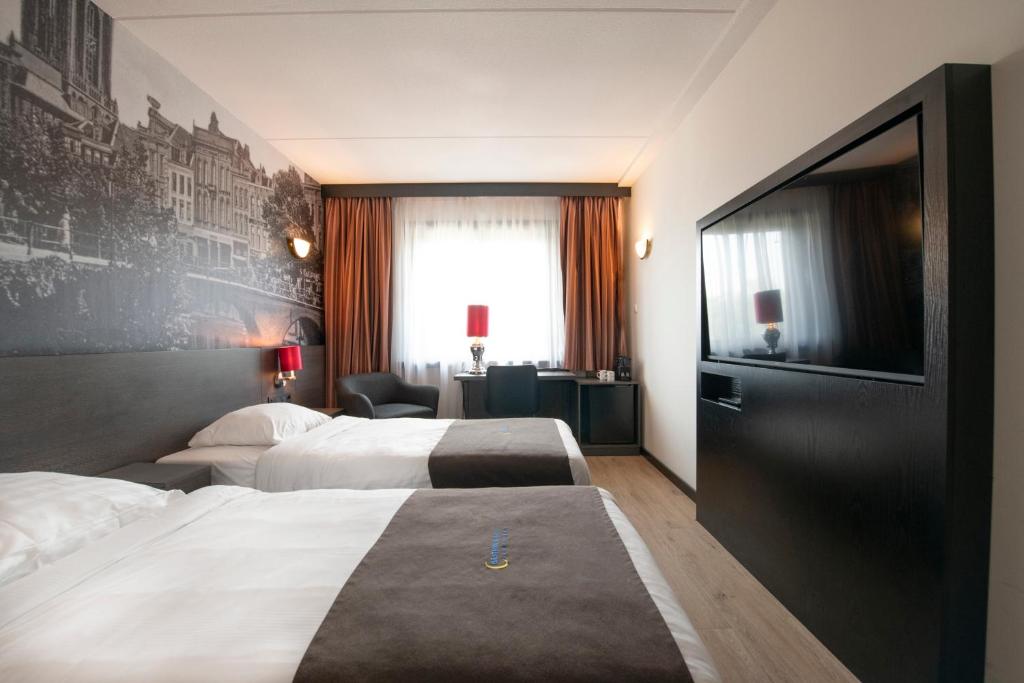 Una habitación de hotel con dos camas y un televisor de pantalla plana. en Bastion Hotel Utrecht, en Utrecht