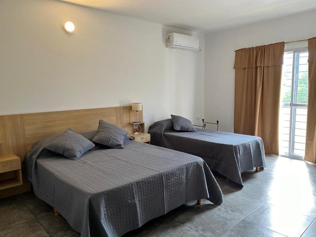 a bedroom with two beds and a window at Complejo Aloe Vera C in Villa Dolores