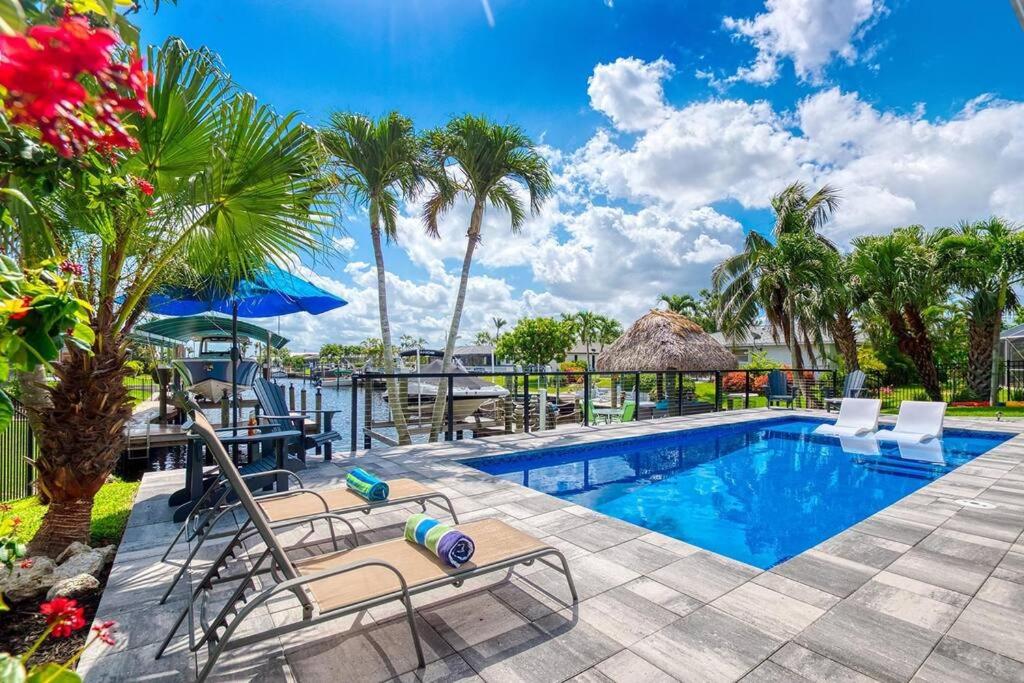 uma piscina num resort com cadeiras e mesas em Villa Jaclyn of Cape Coral! em Cape Coral