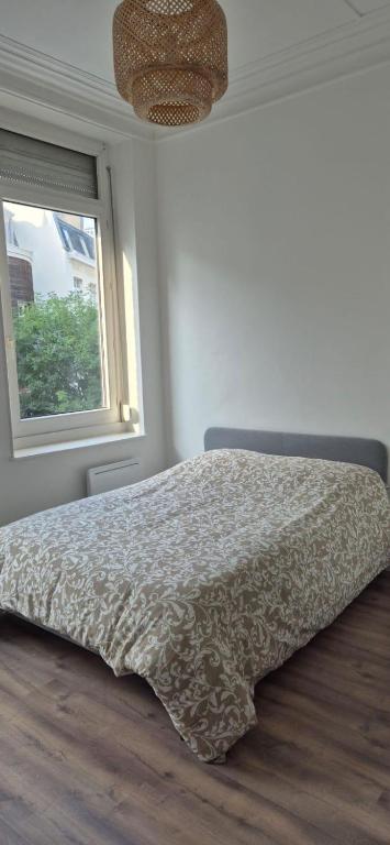 un lit dans une chambre blanche avec une fenêtre dans l'établissement T3 09 Calme et Agréable Parking, à Roubaix