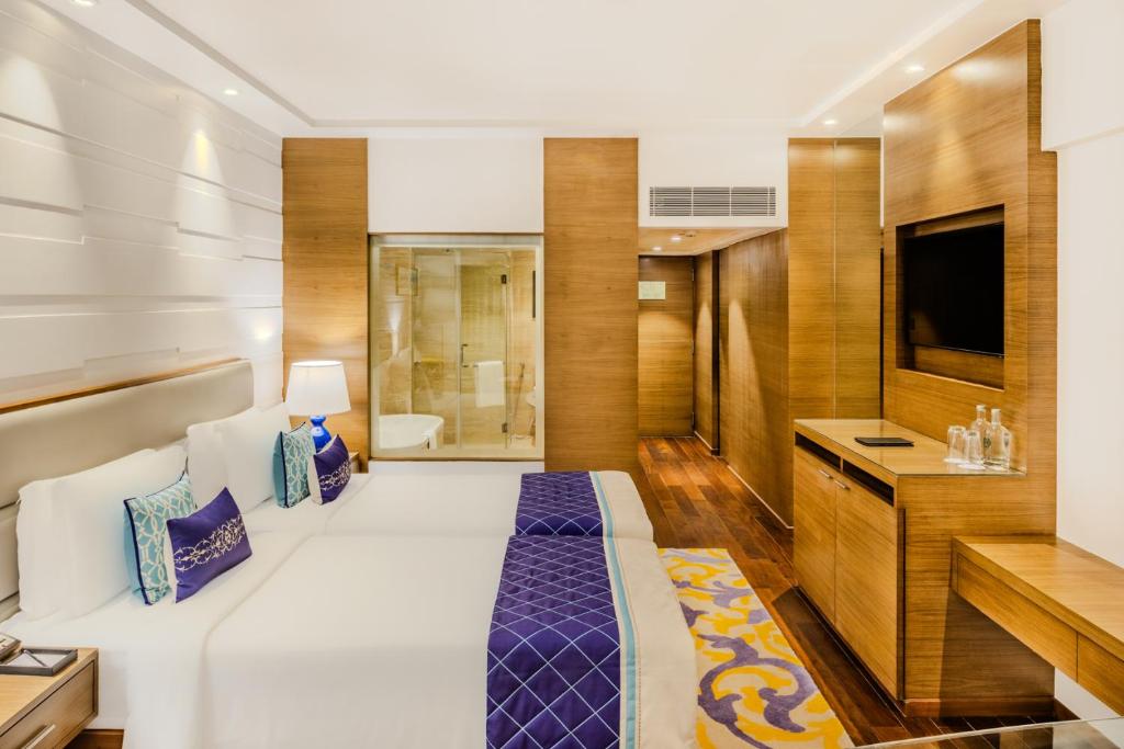 a hotel room with a large bed and a tv at Vivanta Goa, Panaji in Panaji