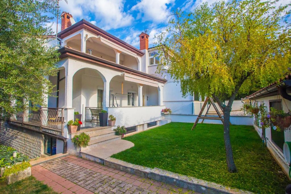 a large white house with a green yard at Apartment Complex Kampic in Poreč