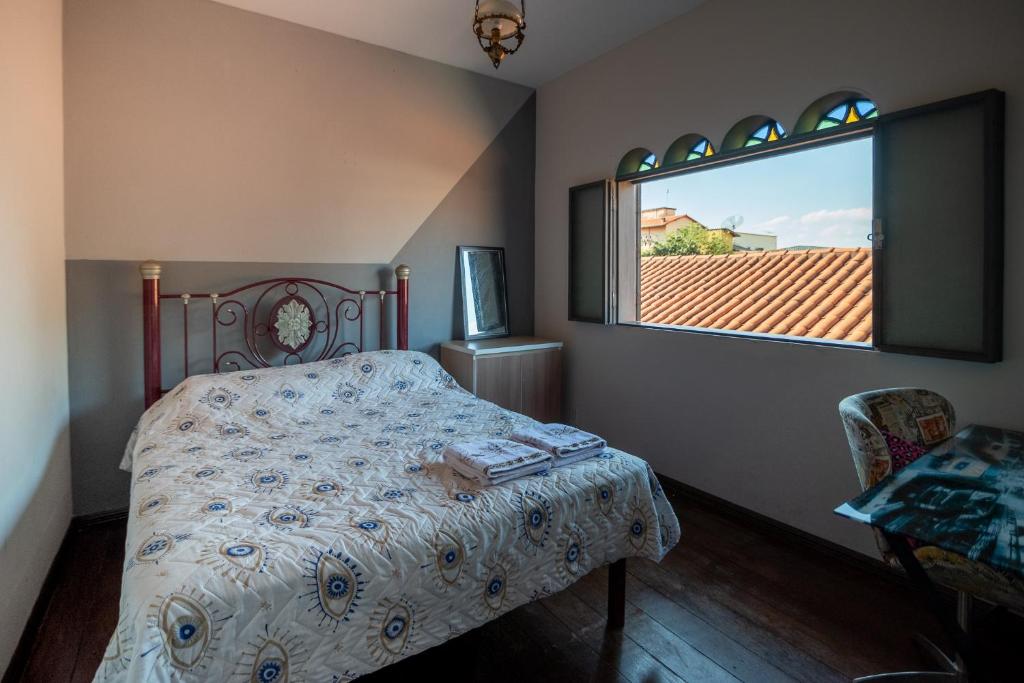 a bedroom with a bed and a window at Espaço Mônica Hospedagem in Brumadinho