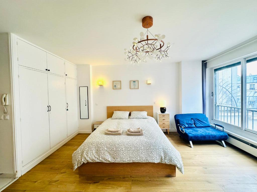 une chambre avec un grand lit et une chaise bleue dans l'établissement Dream Dwell Paris-Deluxe Studio 650m near Arc de Triomphe, à Paris