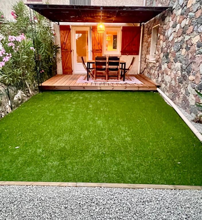 une terrasse avec une pelouse verte en face d'une maison dans l'établissement Superbe logement bord de mer contigu à la Marine de Davia, à Corbara