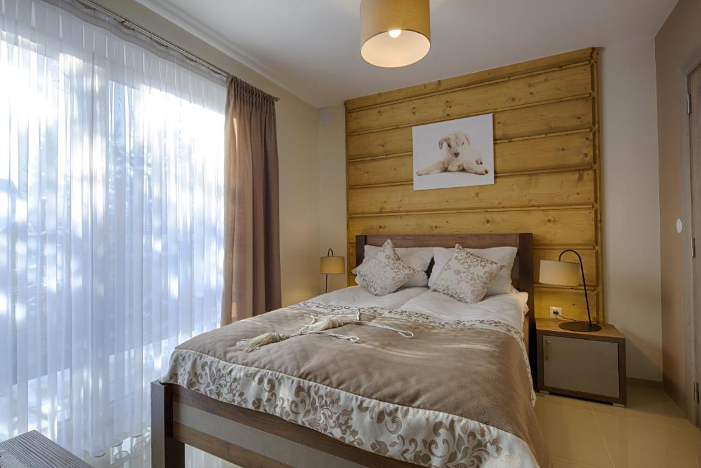 a bedroom with a large bed with a wooden headboard at Gordonówka Residence & SPA- sauna i jacuzzi-przeżyj niezapomniany pobyt in Szaflary