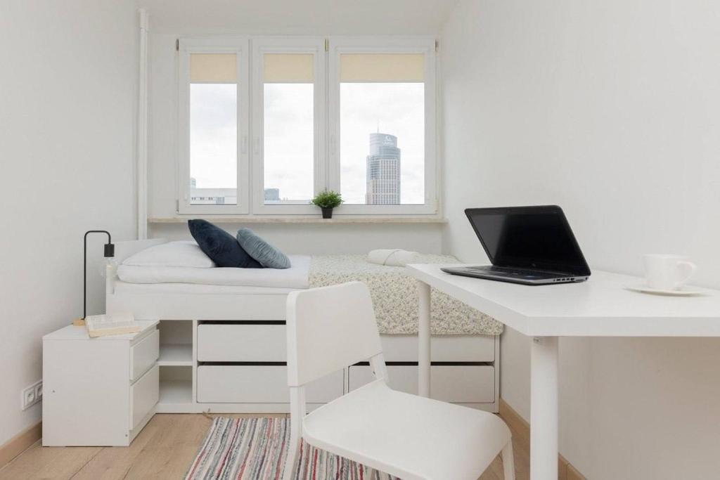 a white room with a desk and a laptop on a bed at HALBY rooms Walicow 20 in Warsaw