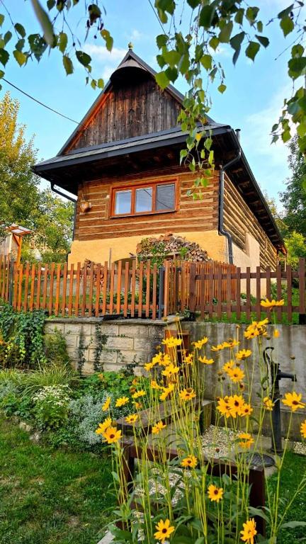 a wooden house with a fence and flowers in the yard at Kdebolotambolo chalupka in Belá