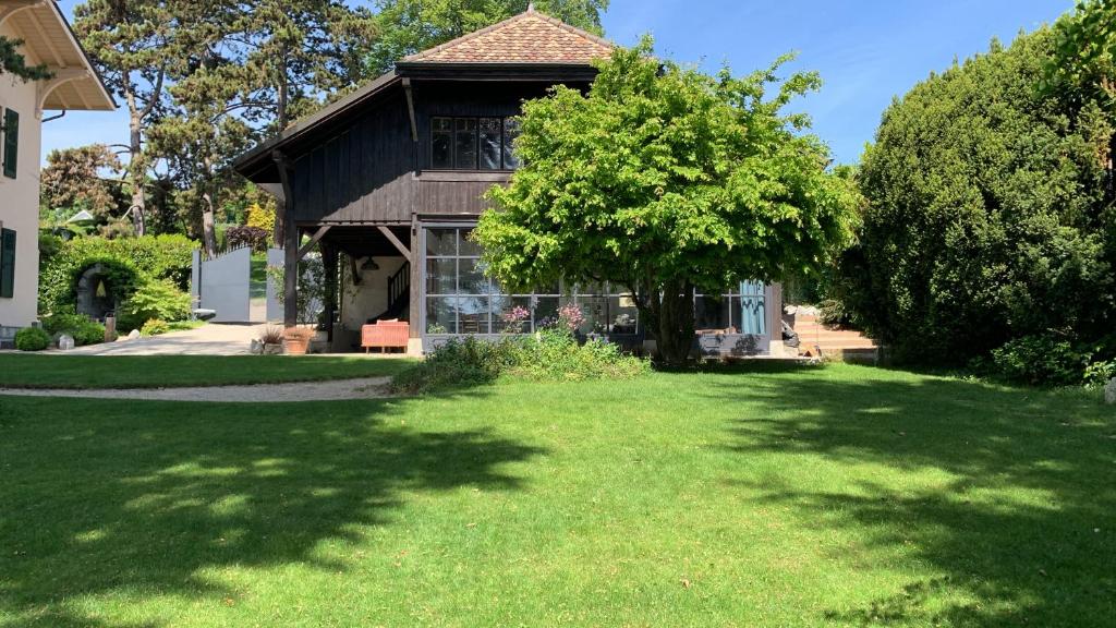 a house with a green lawn in front of it at 'Le Petit Clos Suites'- Charming Getaway on Leman Lake in Nyon