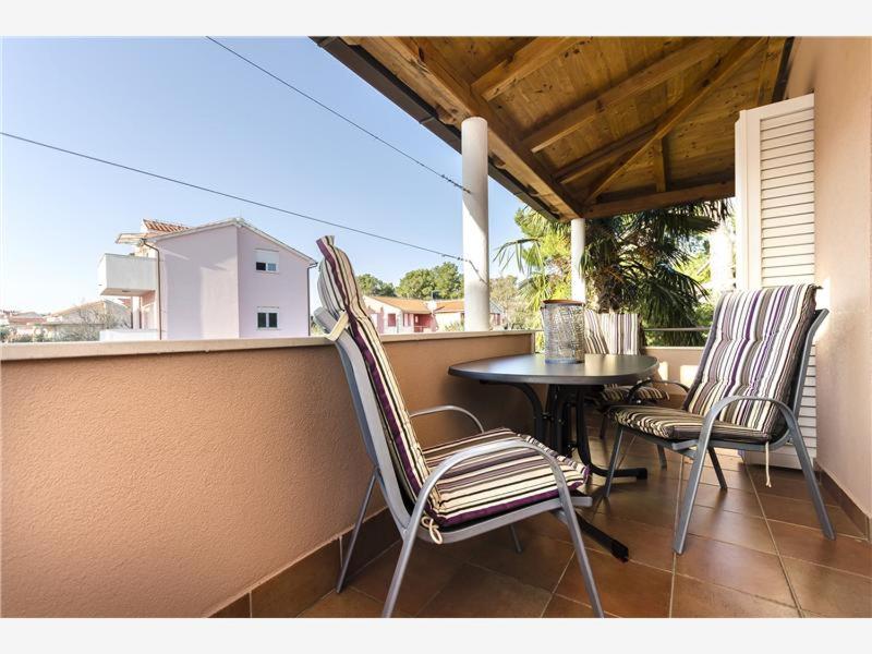 een balkon met 3 stoelen en een tafel op een veranda bij Apartmani Adele in Srima