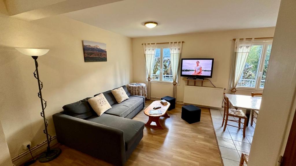 a living room with a couch and a tv at Le Therminus 42 - Le Mont Dore 8pers in Mont-Dore