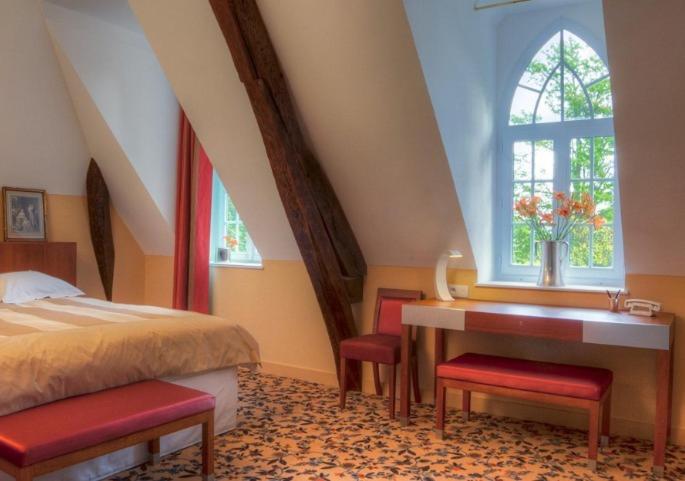 a bedroom with a bed and a desk and a window at Maison d'hôtes Le Manoir de Contres in Contres