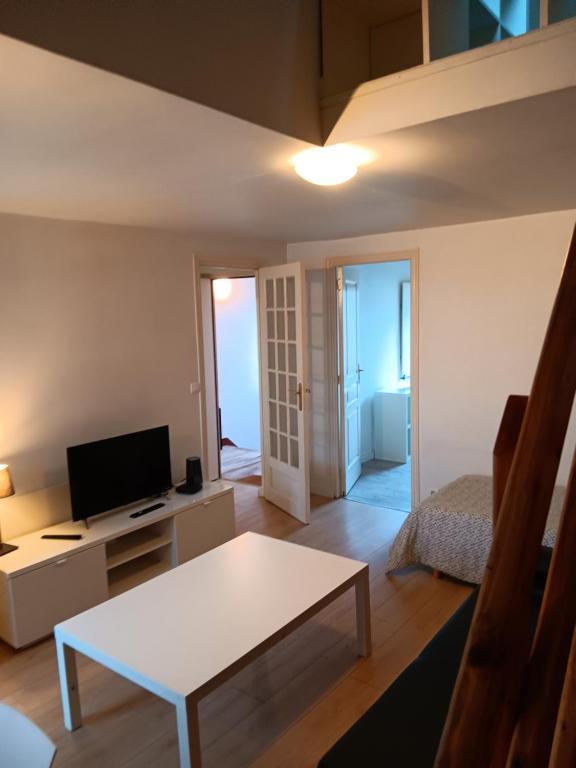 un salon avec une table blanche et une télévision dans l'établissement Suit Mary, à Rennes