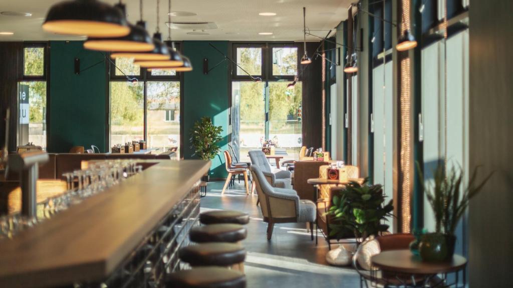 汉堡Holiday Inn - the niu, Bricks Hamburg Eppendorf by IHG的带酒吧的餐厅，酒吧里有椅子和桌子