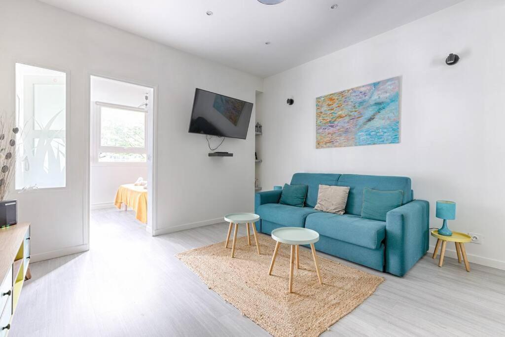 un salon avec un canapé bleu et deux tables dans l'établissement Saint Fargeau Gambetta IV Lovely Apartment 4P 1BR, à Paris