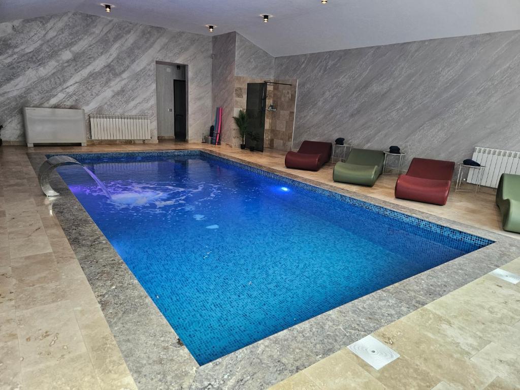 a large swimming pool with blue water in a building at HAPPY TIMES in Bran