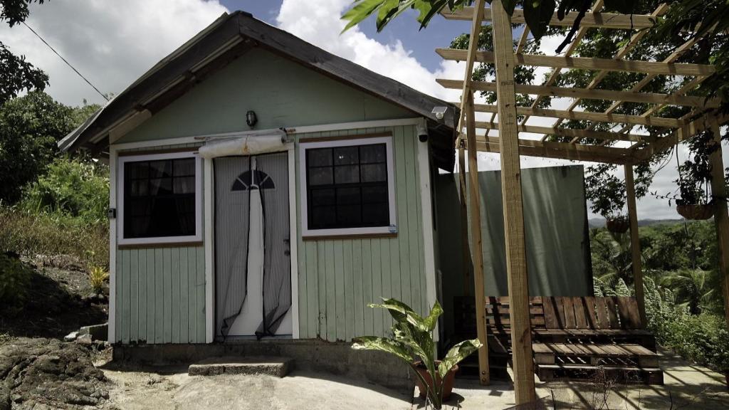 a small green shed with a window and a bench at 1 Bed Cabin - Sleeps 2 - Wifi in Laborie