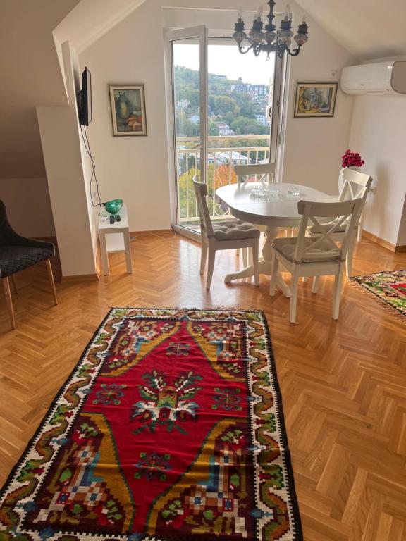 a living room with a table and chairs and a rug at Vrnjacka Hill in Vrnjačka Banja